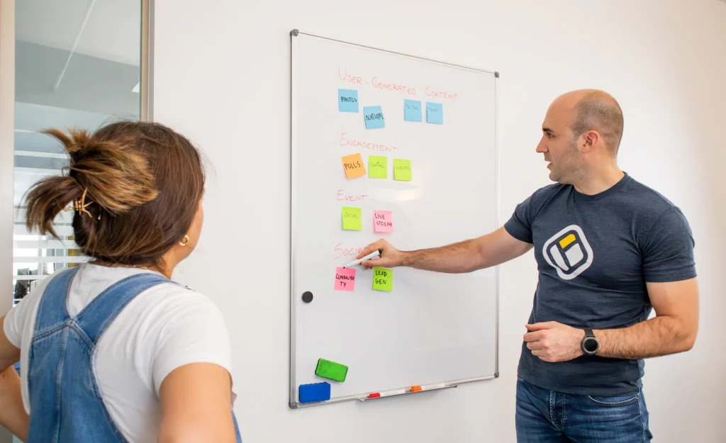 Marketing team grouping sticky notes on a whiteboard during a content ideation session