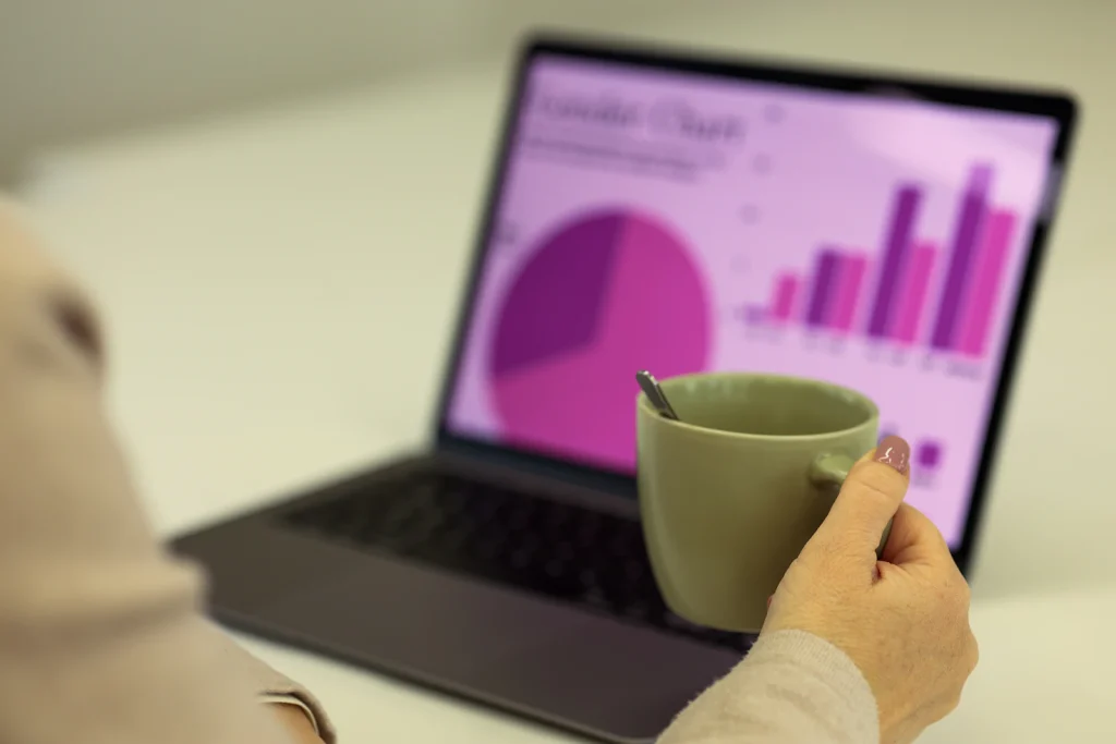 Marketer reviewing pie and bar charts in a data analysis dashboard on a laptop