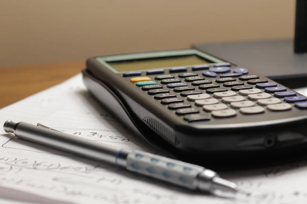 Calculator and pen resting on a printed payroll sheet, the kind of paperwork a paystub generator replaces