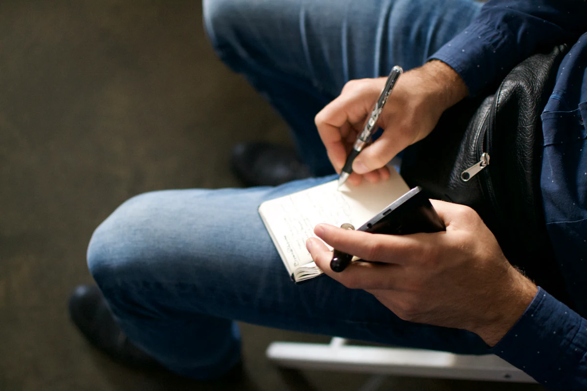 Journalist taking handwritten notes at a conference while gathering expert quotes for a story